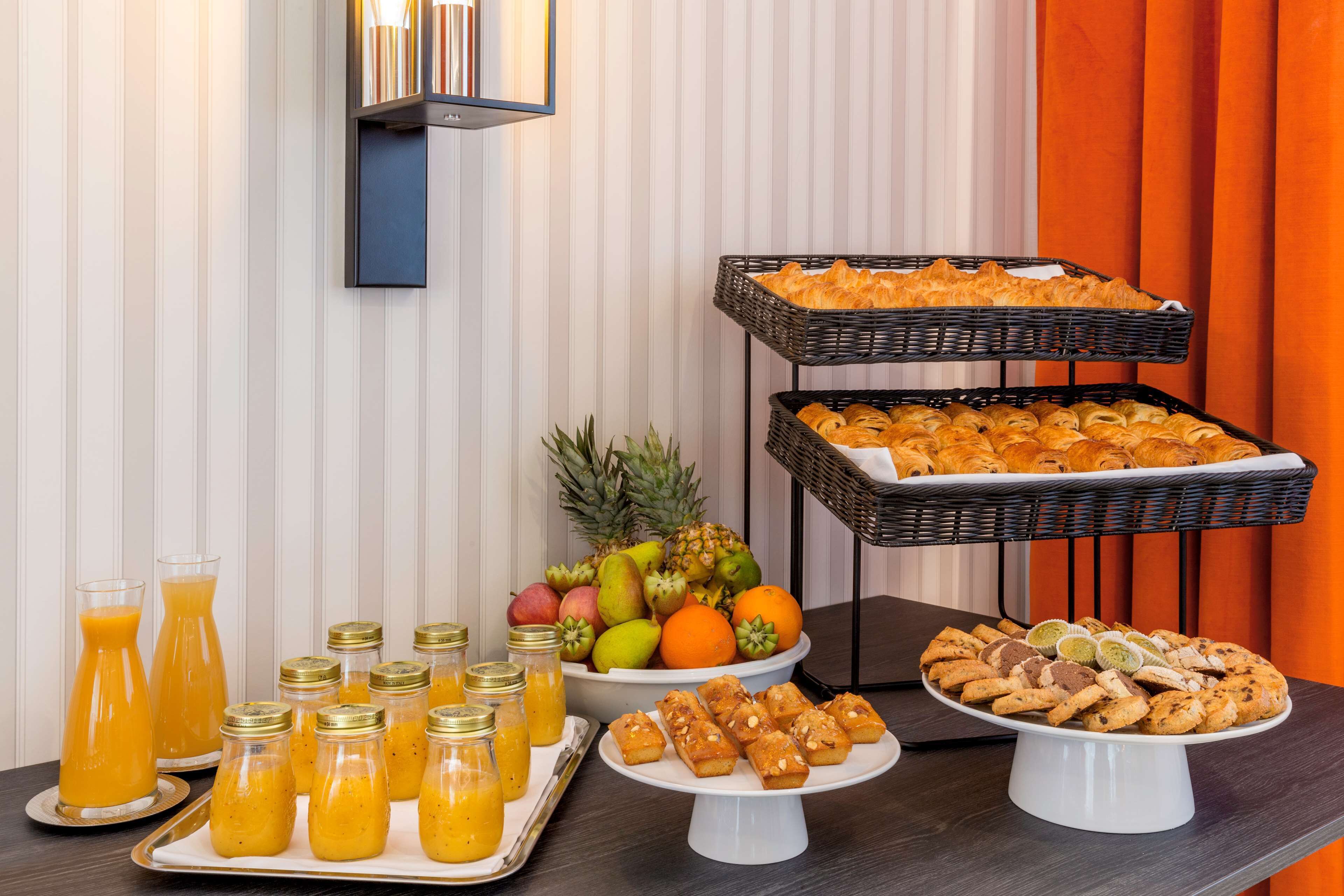 A buffet table with various food items, including fruits, pastries, and juices.
