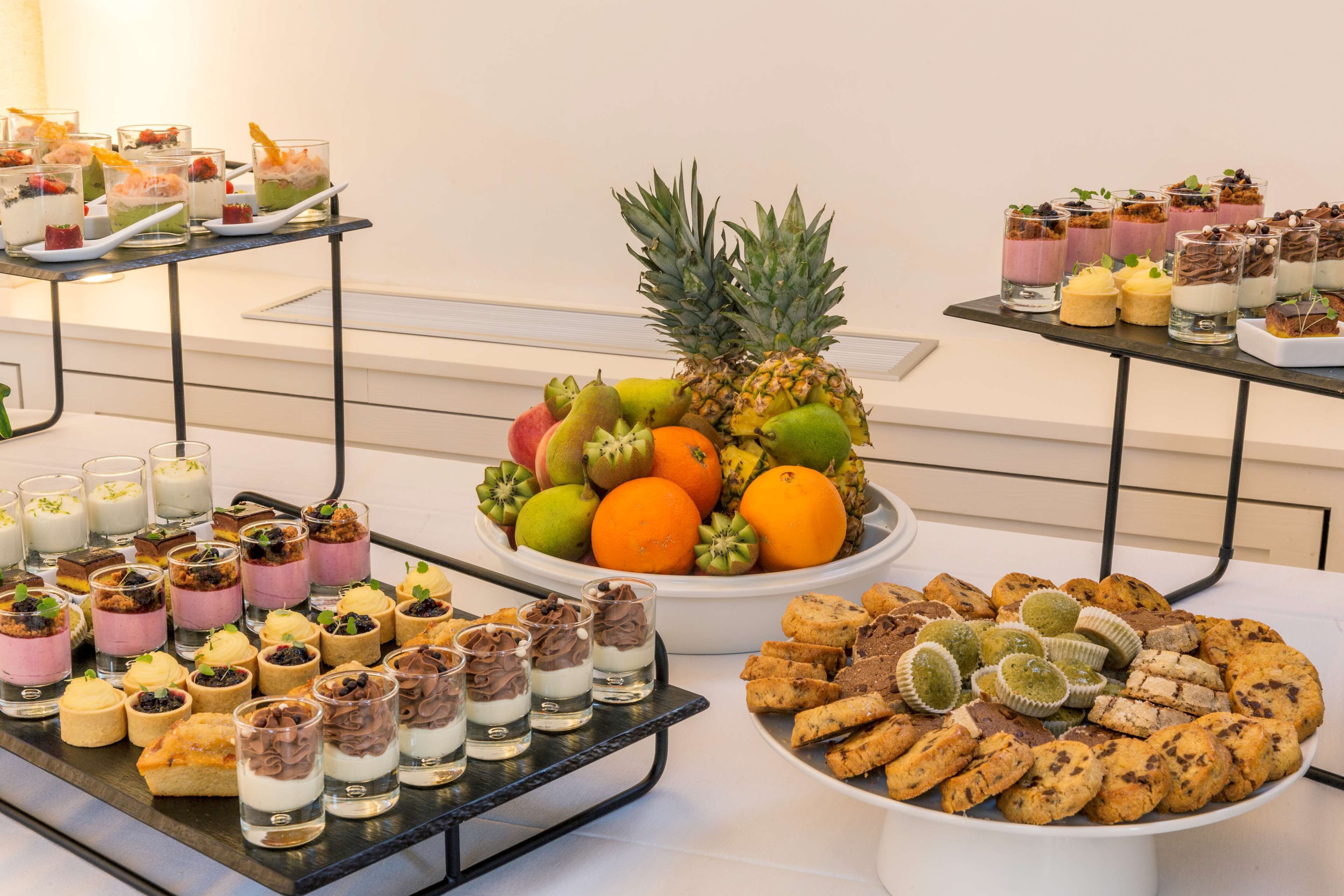 A buffet with various desserts, fruits, and cookies.