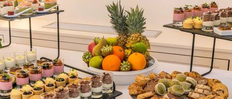 A buffet with various desserts, fruits, and cookies.