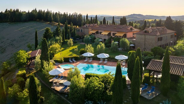 Un'ampia casa con piscina, immersa nel verde e circondata da alberi.