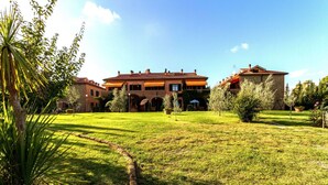 Un grande edificio a due piani con tetto in tegole e un prato ben curato di fronte.