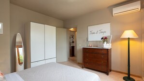 A bedroom with a bed, dresser, mirror, and an air conditioning unit. - Apartment with pool, WIFI, A/C, TV, veranda, pets allowed, panoramic view, close to San Gimignano (Sughera)