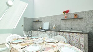 A dining area with a table set for four, a kitchen counter, and a decorative vase on the wall. - Beautiful home in Santa Croce Camerina with WiFi (Santa Croce Camerina)