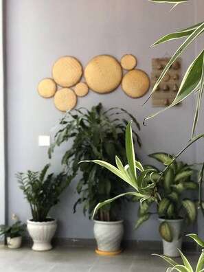 A room with a grey wall decorated with circular wooden wall art, several potted plants, and a tiled floor. - Cosy House Da Nang (Da Nang)