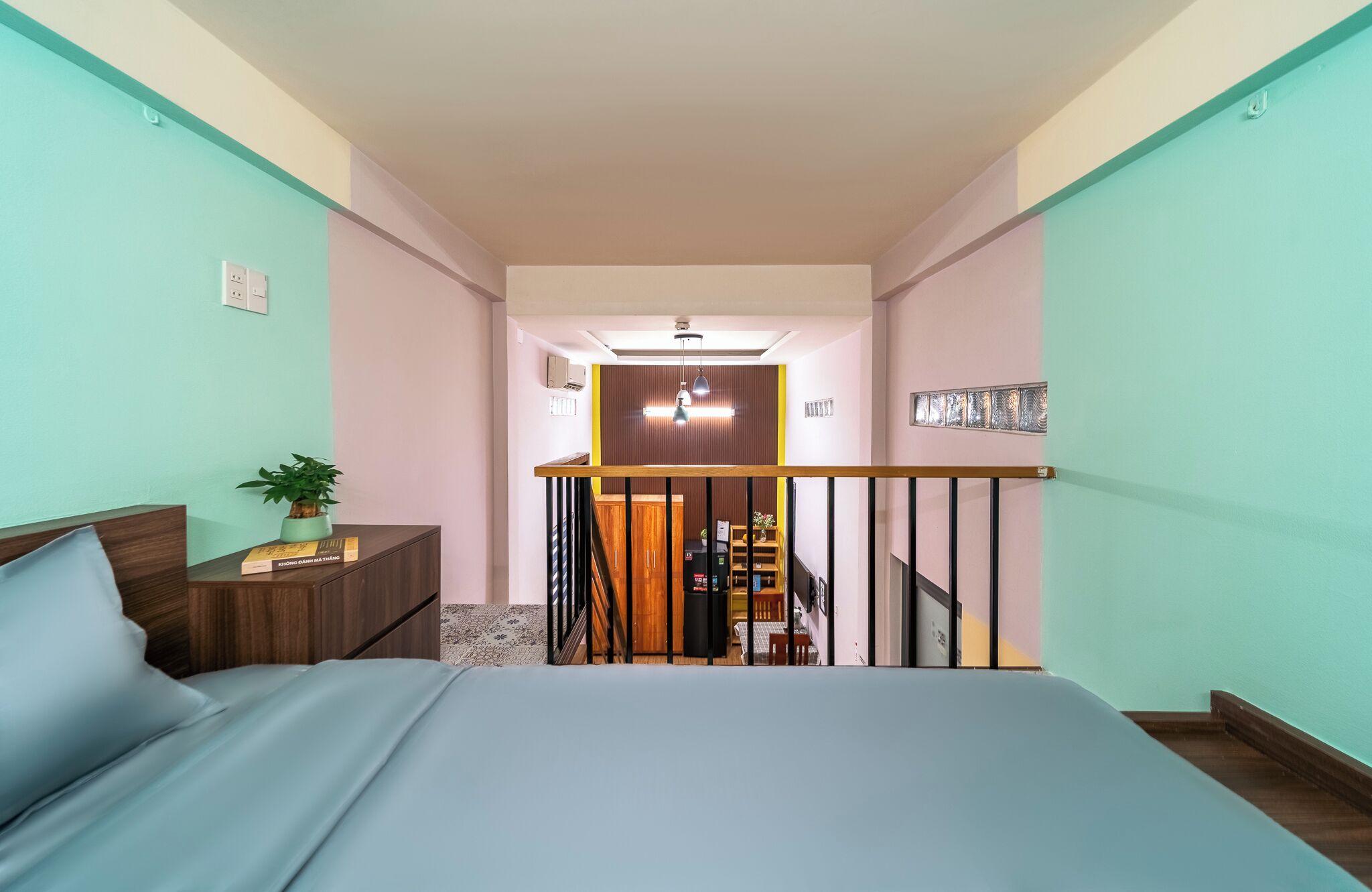 A bedroom with a bed, a nightstand, a plant, and a view of the hallway.