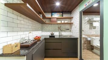 A modern kitchen with white tiled walls, wooden ceiling beams, and a built-in island with a sink.