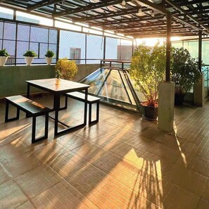 A rooftop terrace with a table and benches, potted plants, and a view of the cityscape. - Cosy House Da Nang (Da Nang)
