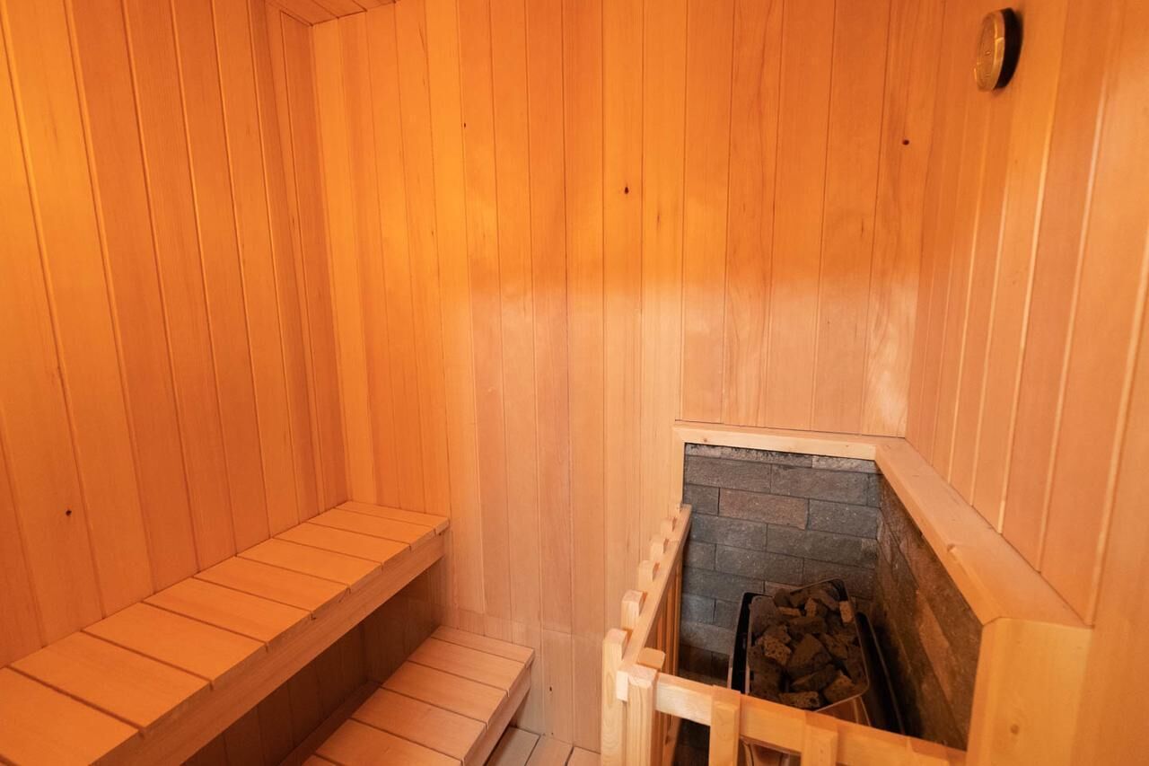 Una sauna in legno con panche e un camino in pietra.