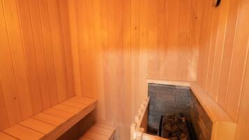Una sauna in legno con panche e un camino in pietra.