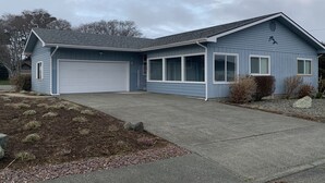 Ein eingeschossiges Haus mit Garage, überdachter Veranda und einem bepflanzten Vorgarten.