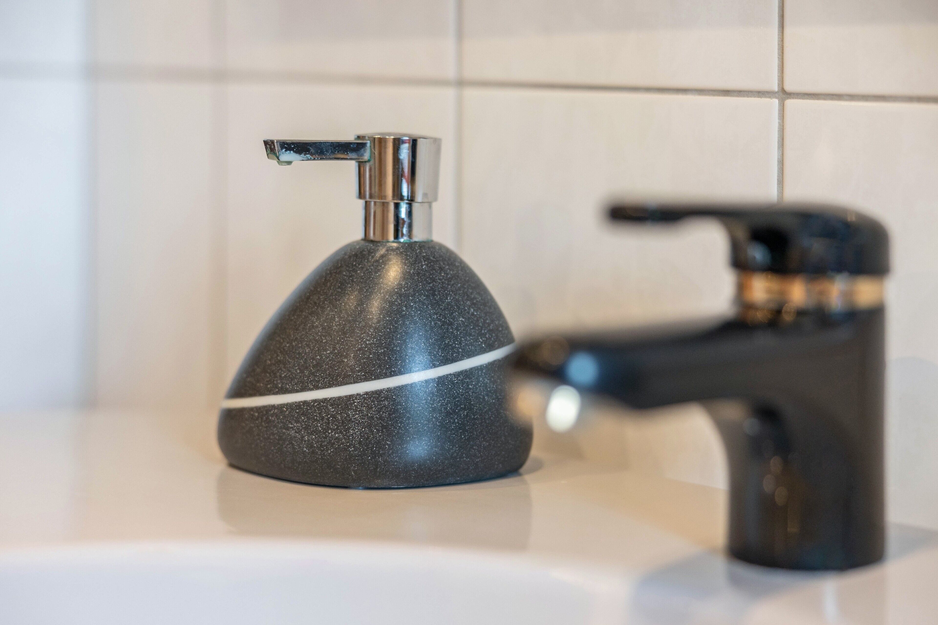 Un baño con un grifo moderno y un dispensador de jabón.