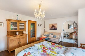 Quarto com cama, armário de madeira, lustre, sofá e área de refeições.