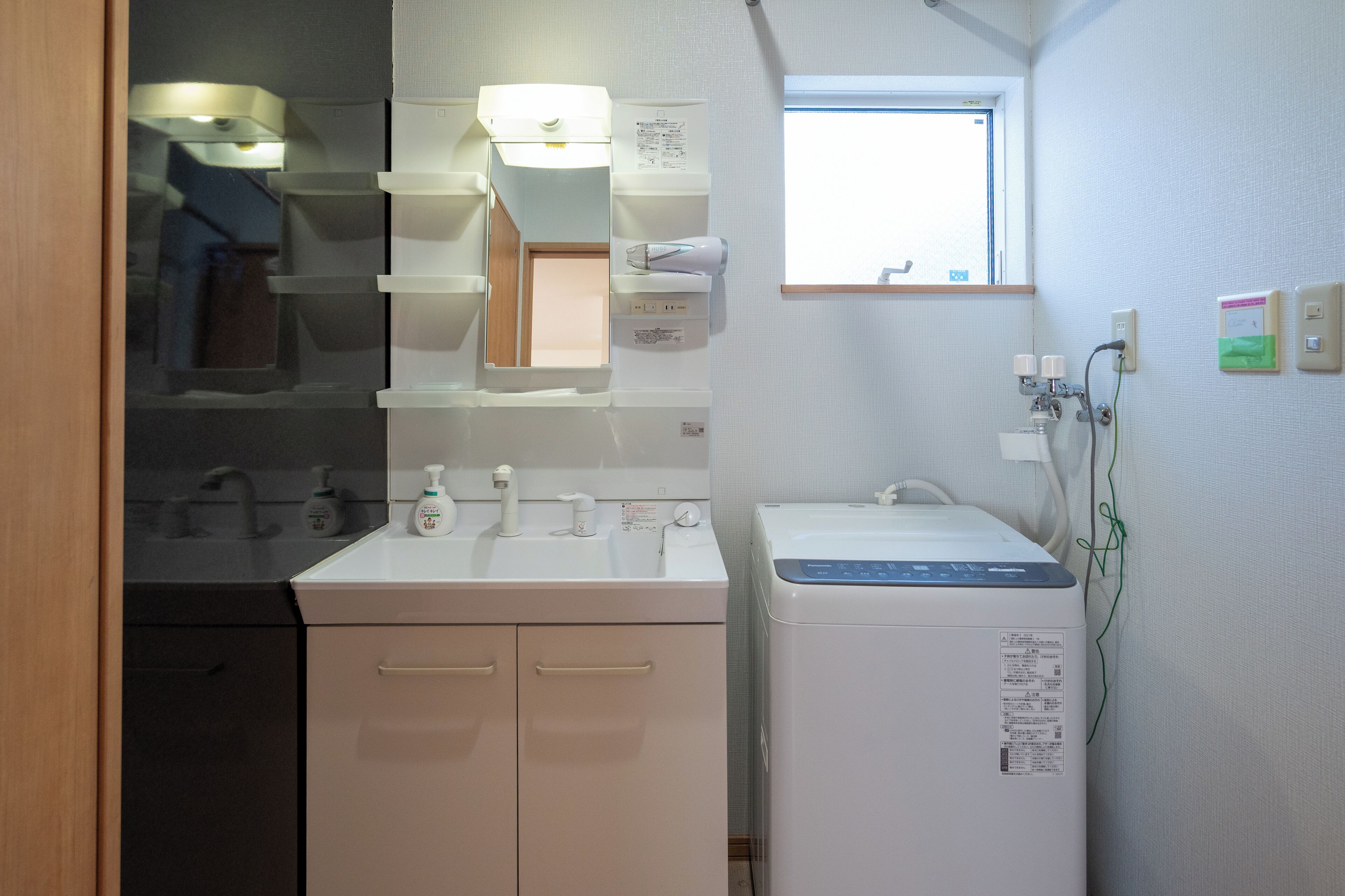 Baño pequeño y funcional con lavamanos, espejo y una ventana.