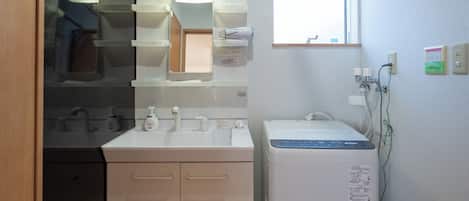 Baño pequeño y funcional con lavamanos, espejo y una ventana.