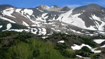 A mountainous landscape with snow patches and green vegetation.