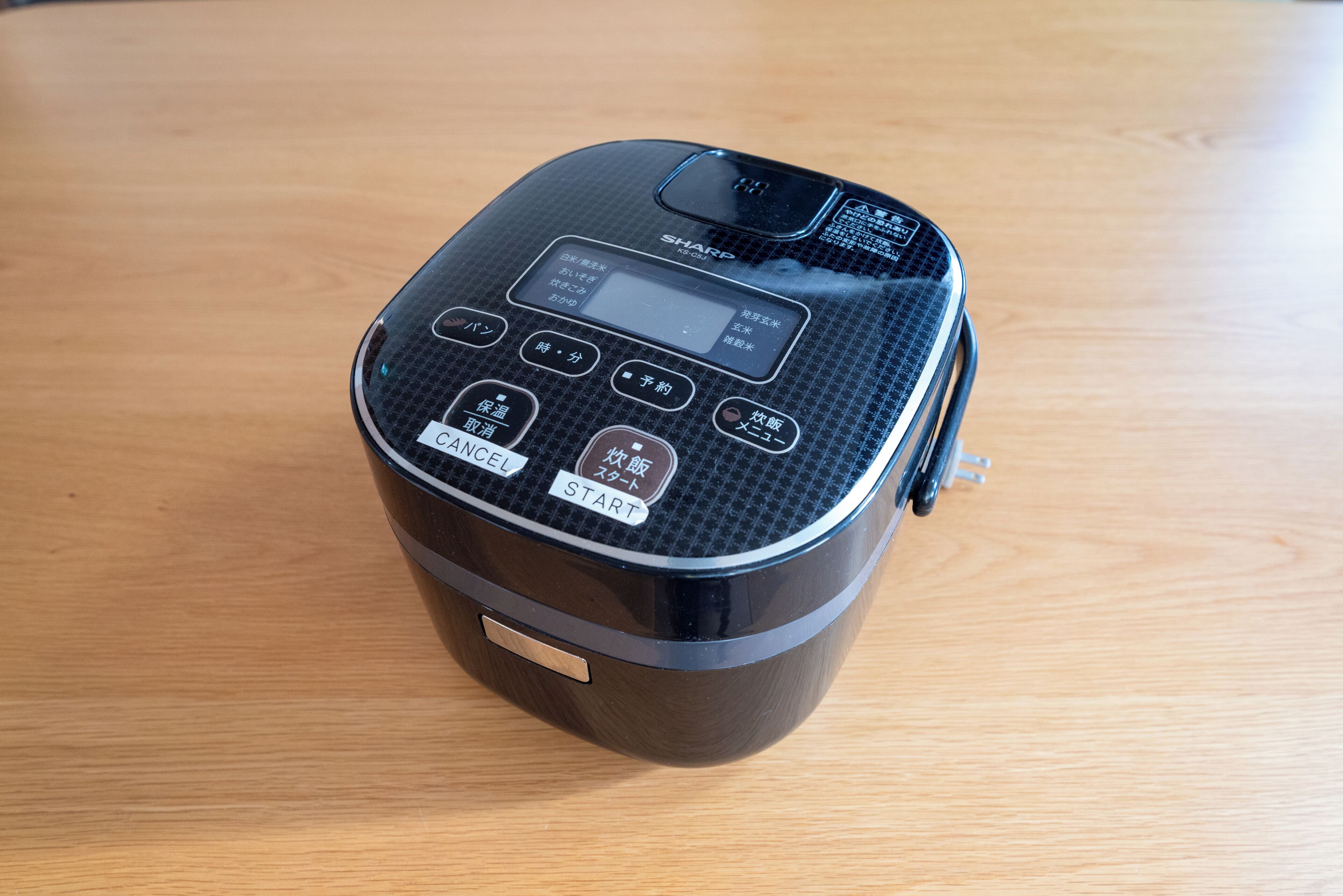 A black portable speaker with a digital display and multiple buttons on a wooden surface.