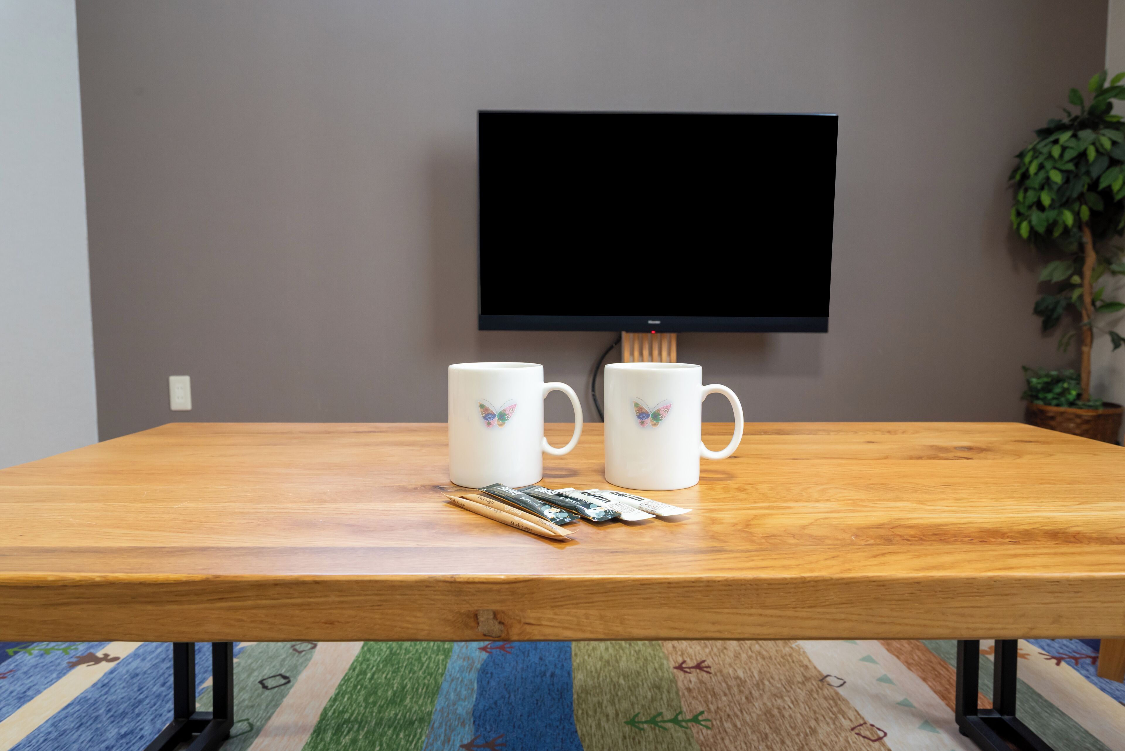 A wooden table with two white mugs and a packet of cigarettes.