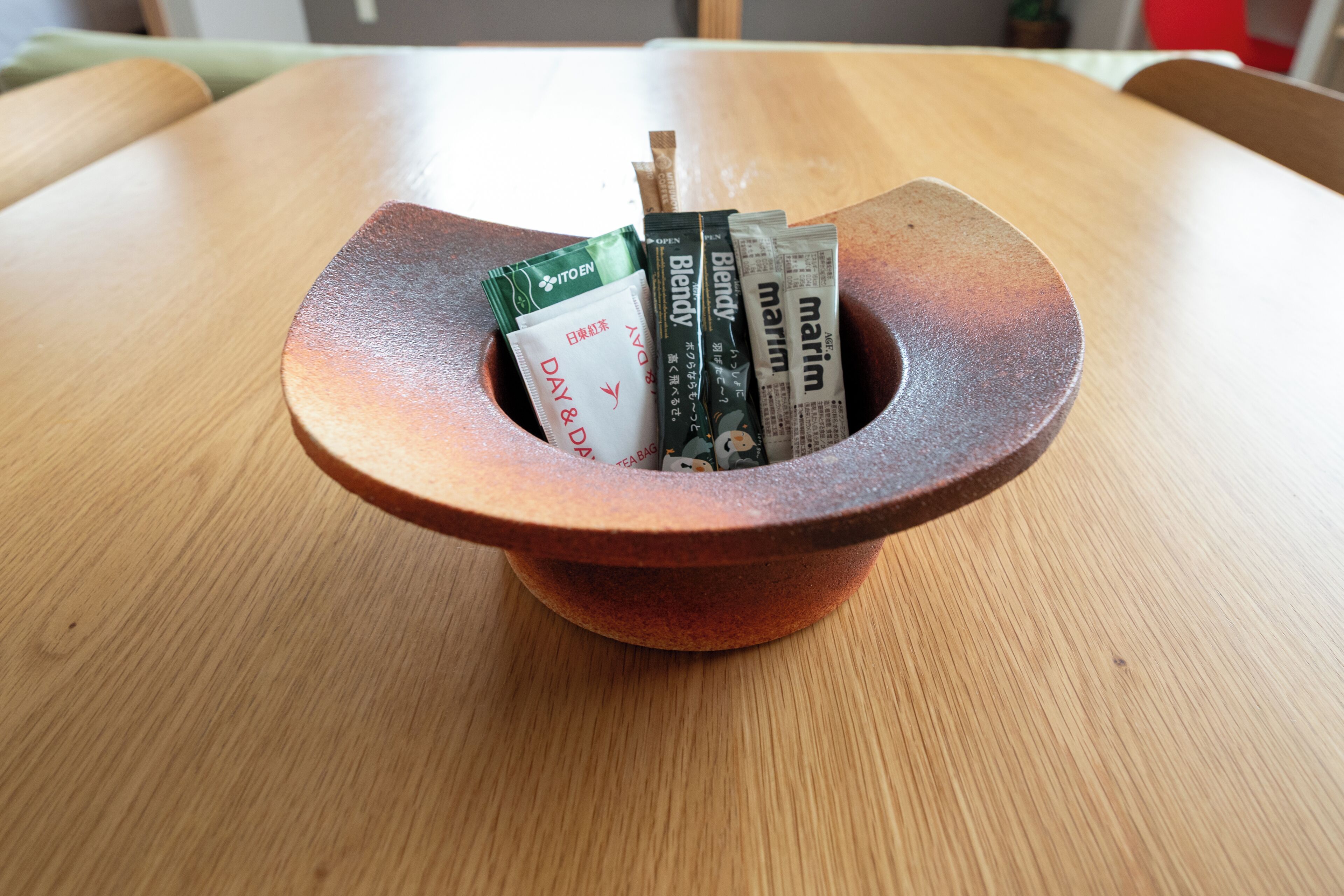 A wooden table with a round, shallow bowl containing several books and a green packet.