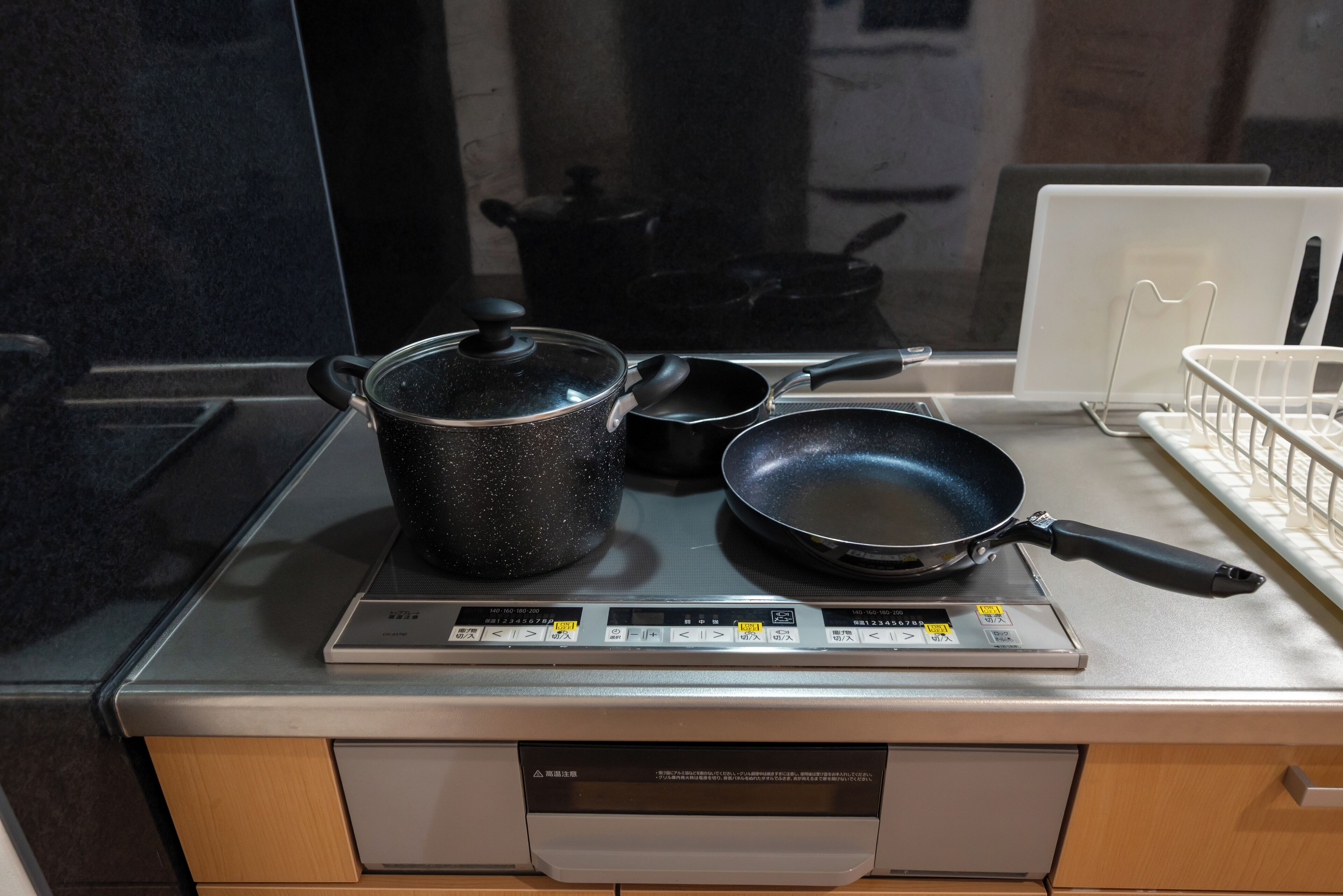 A kitchen with a stove, a frying pan, and a pot on it.