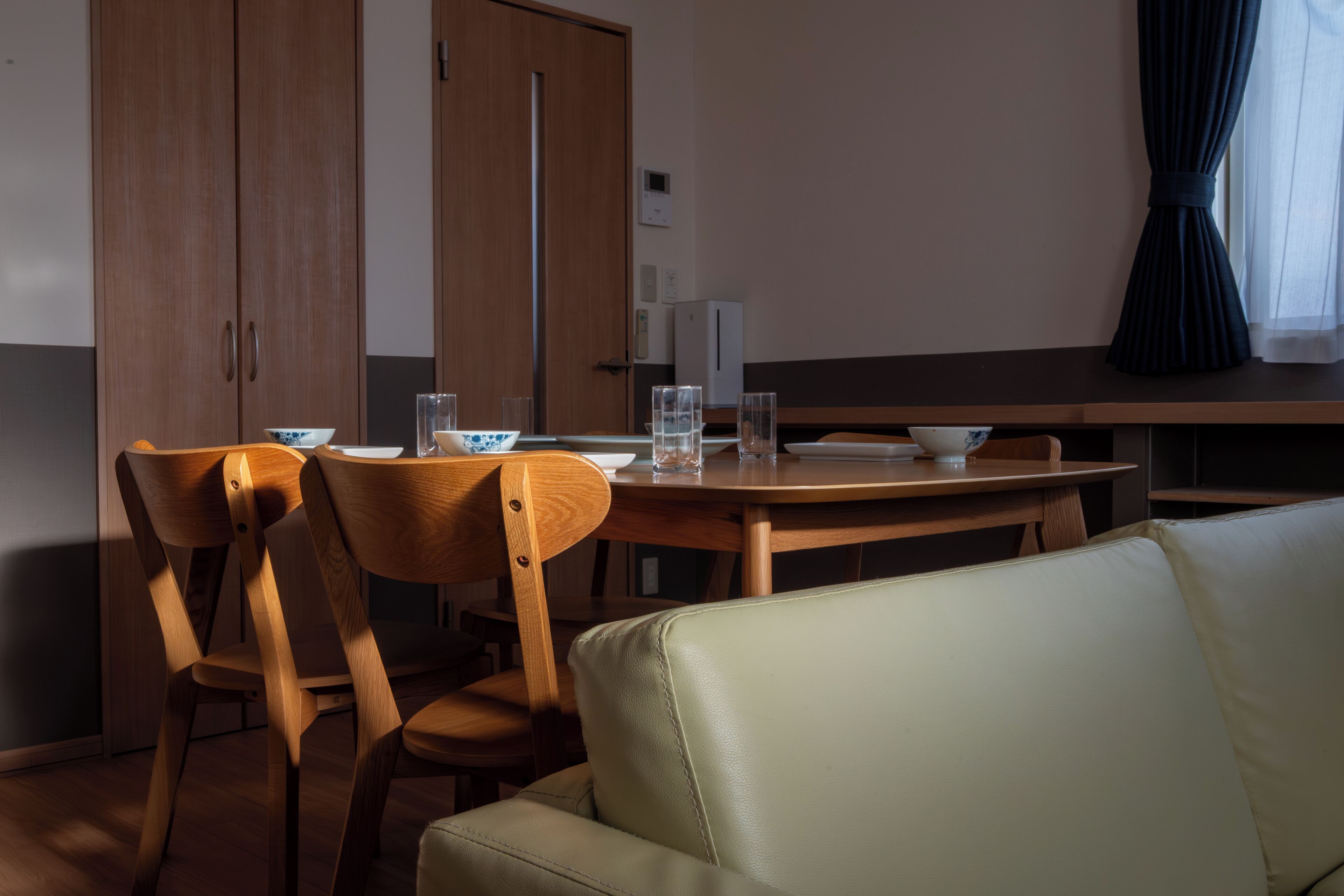 A dining area with wooden chairs, a table, and a sofa.