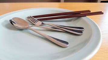 A plate with a spoon, fork, and chopsticks on a table.