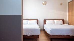 Een kamer met twee bedden, een klok aan de muur en een kledingkast.