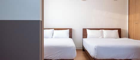 A room with two beds, a clock on the wall, and a wardrobe.