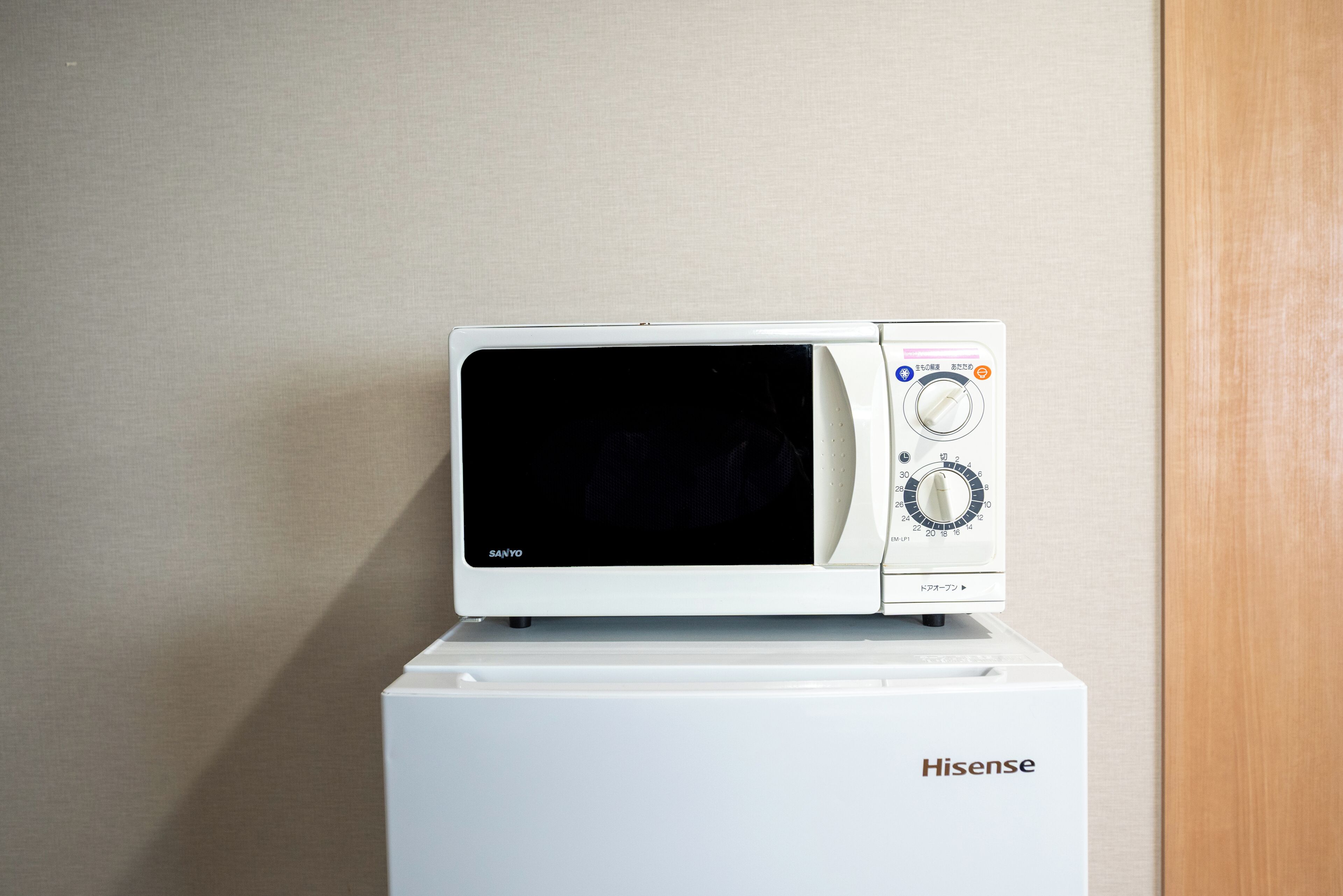 A white Hisense microwave on top of a white Hisense refrigerator.