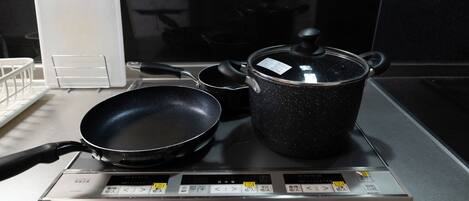 A kitchen with a stove, a frying pan, and a pot with a lid.