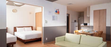 A modern room with a bed, a sofa, a dining table, and a kitchen area.