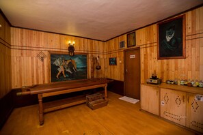 Een kamer met houten lambrisering, een biljarttafel, een schilderij en een kast met flessen.