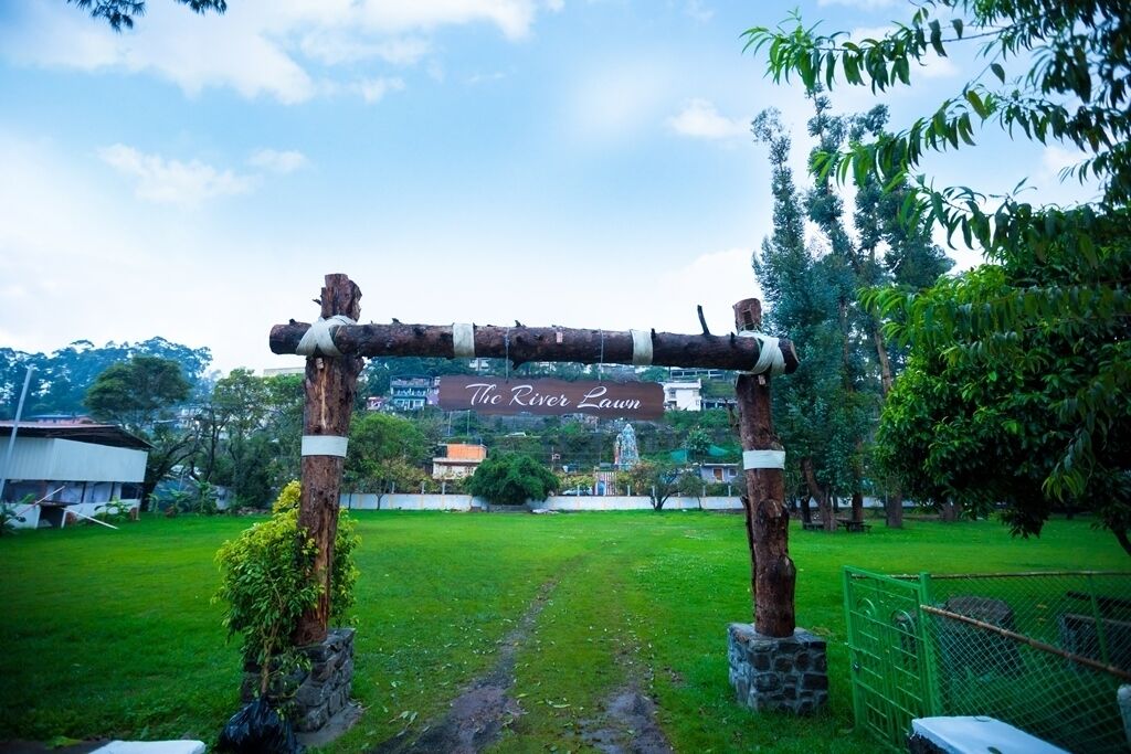 An outdoor entrance with a wooden archway labeled "The River Lawn."