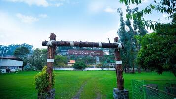An outdoor entrance with a wooden archway labeled "The River Lawn."