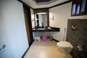 Een badkamer met toilet, wastafel, spiegel en een klein opstapkrukje.