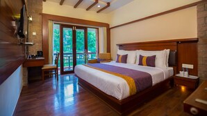 A spacious bedroom with a large bed, wooden headboard, and a desk with a chair. - Hotel Kodai International (Kodaikanal)