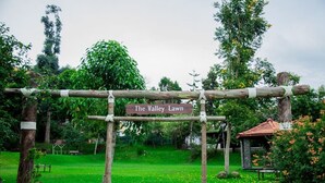 A wooden archway with a sign reading "The Valley Lawn" in a lush garden setting. - Hotel Kodai International (Kodaikanal)