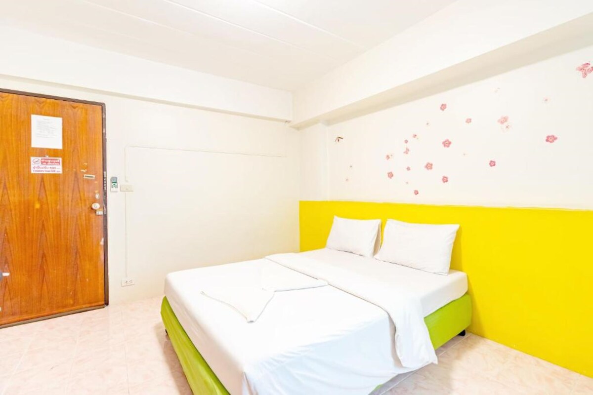 Una stanza con un letto, una porta in legno e un muro decorato con motivi floreali.