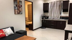 A compact living space with a kitchenette, a dining area, and a seating area with a sofa and a small table. - Golite Hostel-Albay (Legazpi)