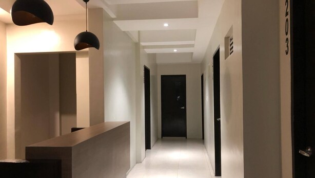 A modern hotel hallway with a reception desk, pendant lighting, and a clean, minimalist design. - Golite Hostel-Albay (Legazpi)