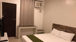 A hotel room with a bed, a desk, a chair, a TV, and an air conditioning unit. - Golite Hostel-Albay (Legazpi)