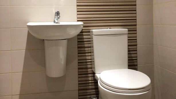 A small, modern bathroom with a white sink, toilet, and a mirror above the sink. - Golite Hostel-Albay (Legazpi)