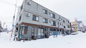 A multi-story building with large windows and air conditioning units. - Stay in Otaru (Otaru)