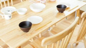 A wooden dining table with white and black bowls, chopsticks, and a white mug with a bear design. - Stay in Otaru (Otaru)