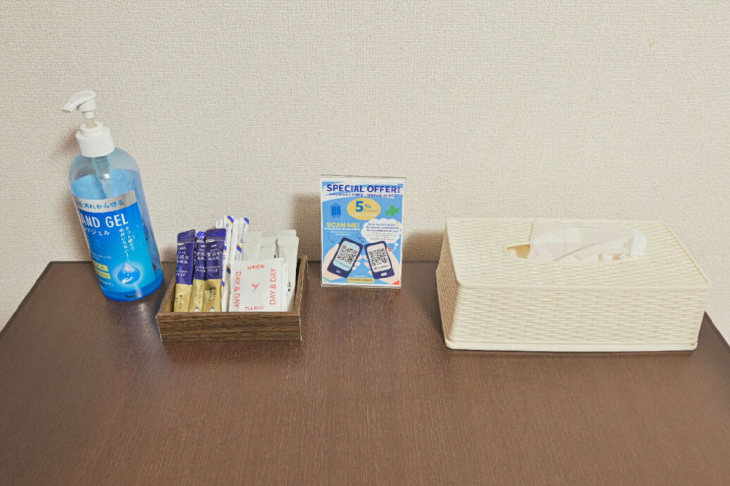 A table with a blue hand gel bottle, a box of tissues, and a tissue box.
