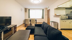 A modern living room with a sofa, TV, and dining area.