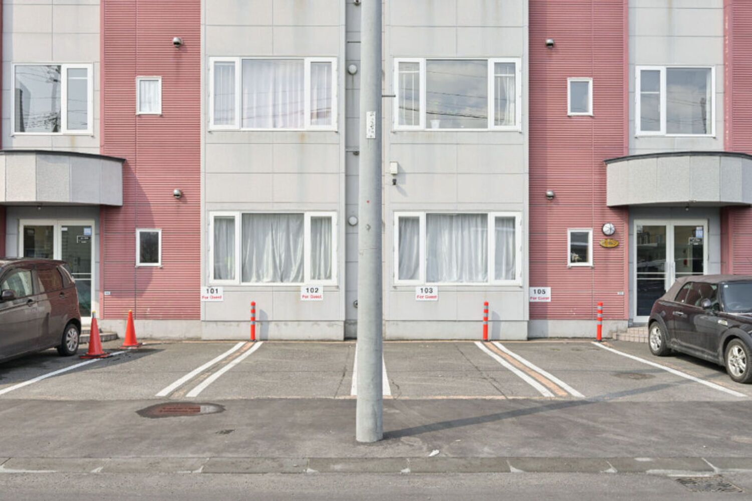 A multi-story building with numbered parking spaces, a central pole, and a vehicle parked on the left.