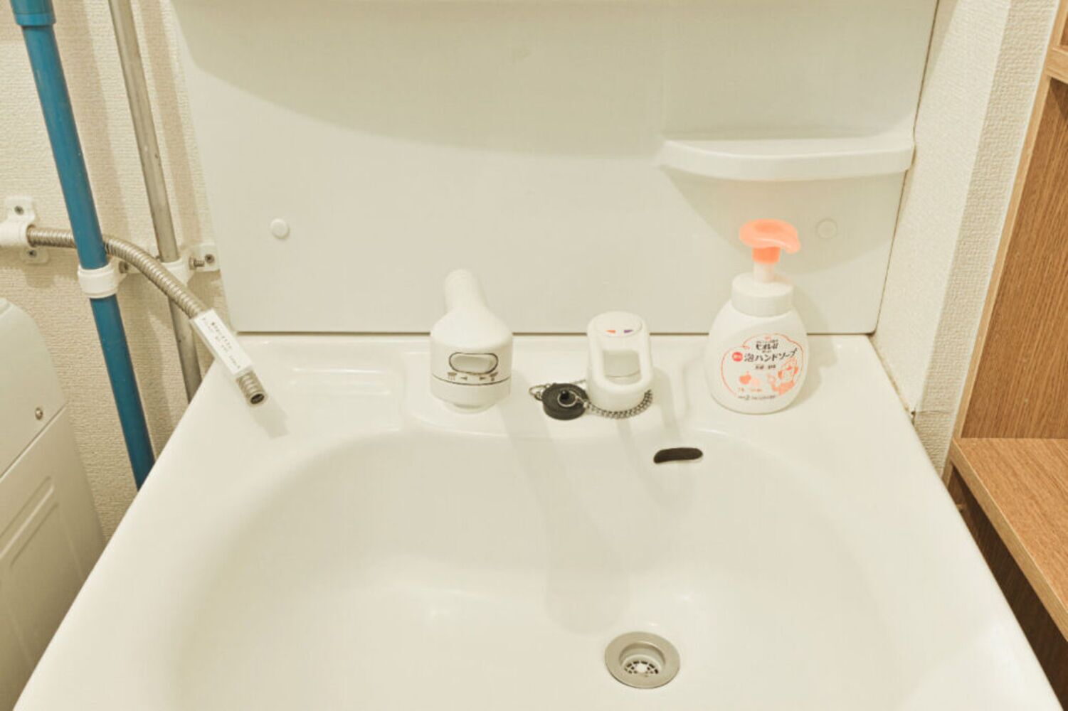 A bathroom sink with a faucet, soap dispenser, and a bottle of liquid soap.