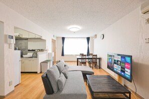 Ein kompakter Wohnbereich mit Küchenzeile, Sofa, Esstisch und Flachbildfernseher.