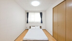 A bedroom with a single bed, a wooden wardrobe, and a window with curtains.