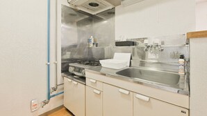 A kitchen with a stainless steel sink, a stove, cabinets, and a ventilation hood.